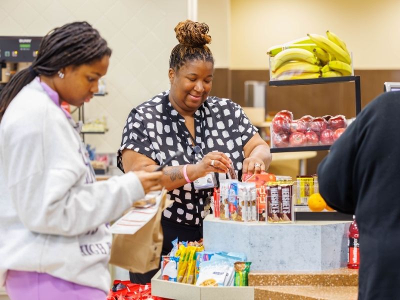 Kimberly Wilkerson, center, retail manager, adds snacks to displays at UMMC’s cafeteria at University Hospital.