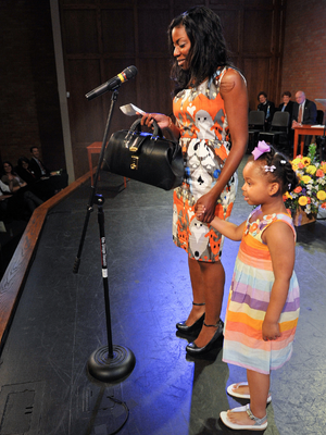 The future Dr. Keisha Bell, holding a physician's medical bag and the hand of her daughter, Jai, announces her UMMC residency match on Match Day 2012. (File photo)