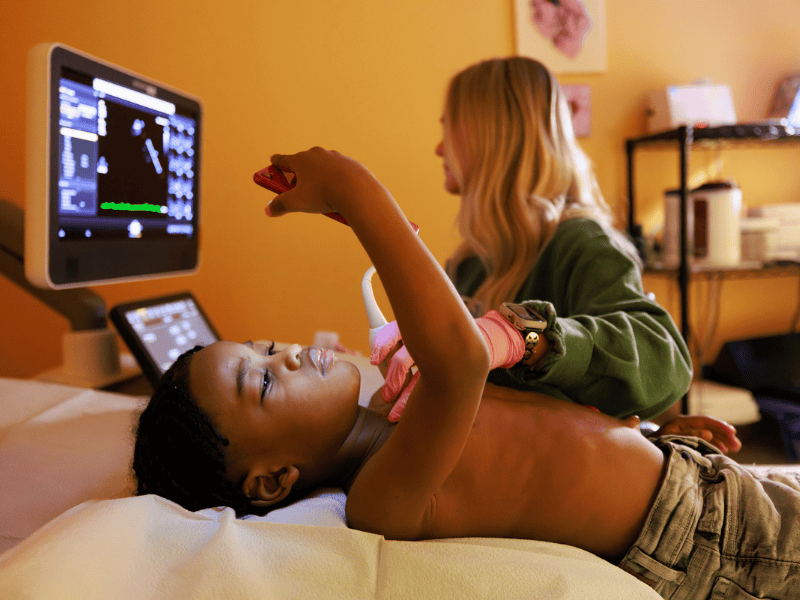 Jerome Brooks of Macon, a patient at Children's of Mississippi's Tupelo Specialty Clinic, watches a video on his mother's phone while getting an echocardiogram by Reese Fraidy, sonographer.