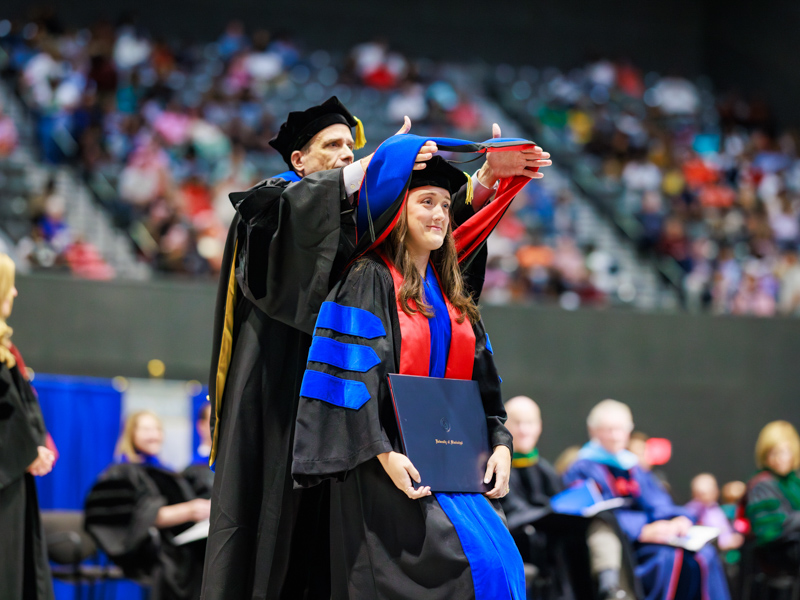 Taylor Ward Lefler, PhD in biostatistics and data science graduate, receives her hood from the John D. Bower School of Population Health. Joe Ellis/ UMMC Communications