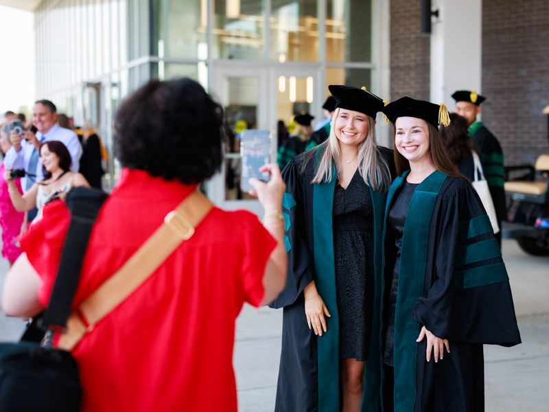 Doctor of Physical Therapy graduates Makenzie Ryals and Halea Wood pose for Halea's mother Jenny Wood. Joe Ellis/ UMMC Communications
