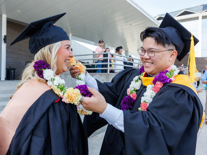 Payton Rogers, MSN graduate, receives a lei from friend Kyle Voong who received a masters in bio medical sciences. Jay Ferchaud/ UMMC Communications