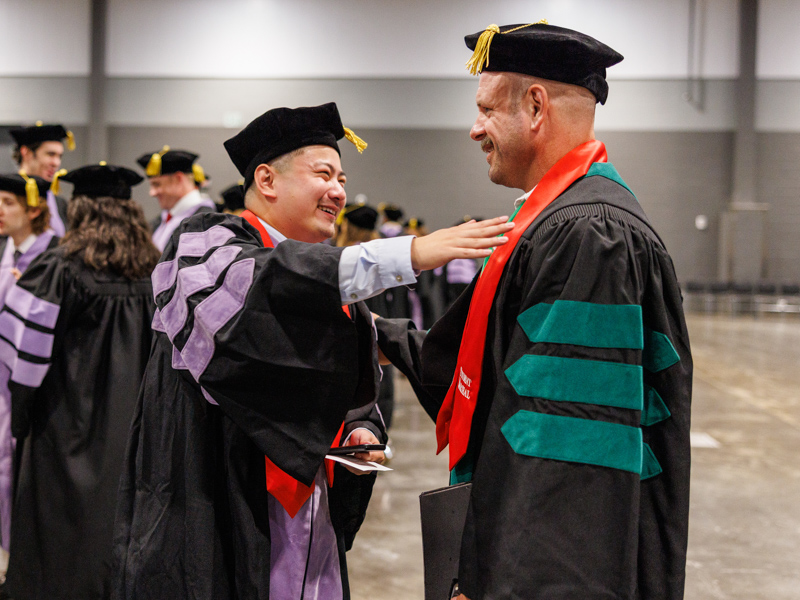 Andy Li, left, School of Dentistry Marshall of the Class with Chris Glasgow, School of Medicine Marshall of the Class give well wishes to each other just before the Commencement ceremony begins. Jay Ferchaud/ UMMC Communications