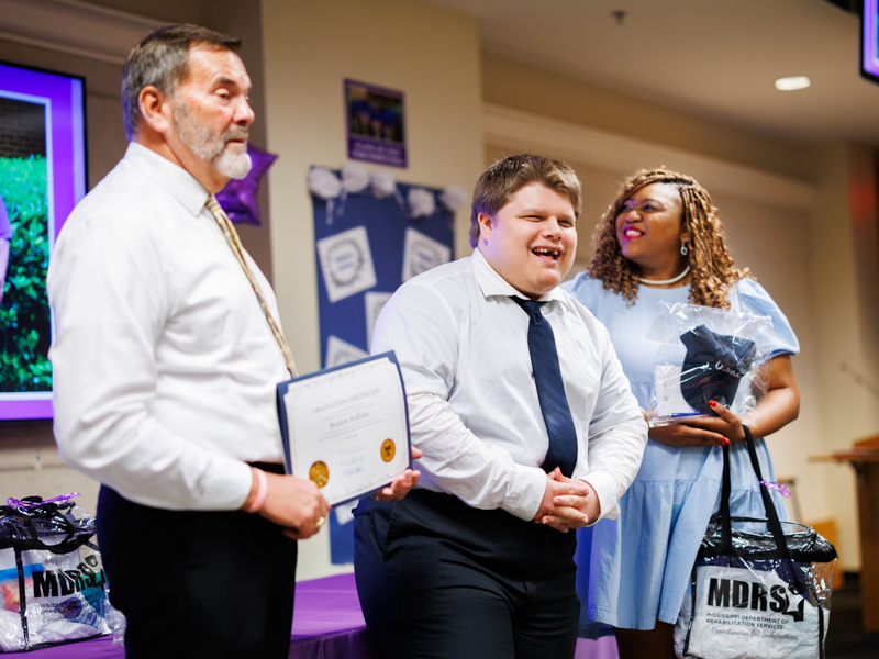 From left, Tommy Burnham, of Project SEARCH, Braden Holliday, of Brandon, among seven who completed the program in 2025, Jasmine Lee, teaching assistant and job skills trainer in the program.