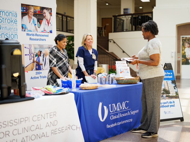 Merlin Manogaram, left, with Sponsored Programs, and Cathy Hudgins, RN, research nurse manager, speak with Jannifer Lott of Clinton about UMMC's Clinical Trials programs.