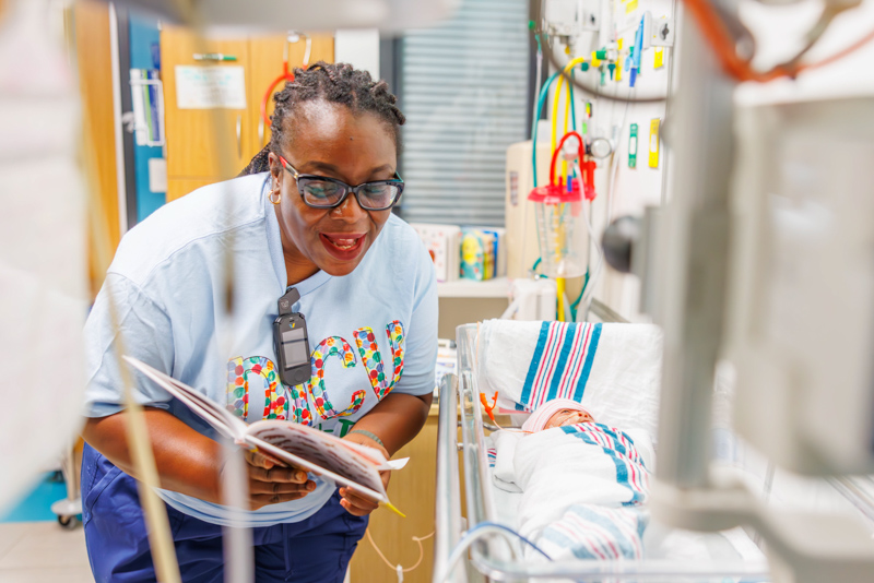 Dr. Mobolaji Famuyide, chief of pediatric neonatology, reads to Sariyah Luckett of Jackson.