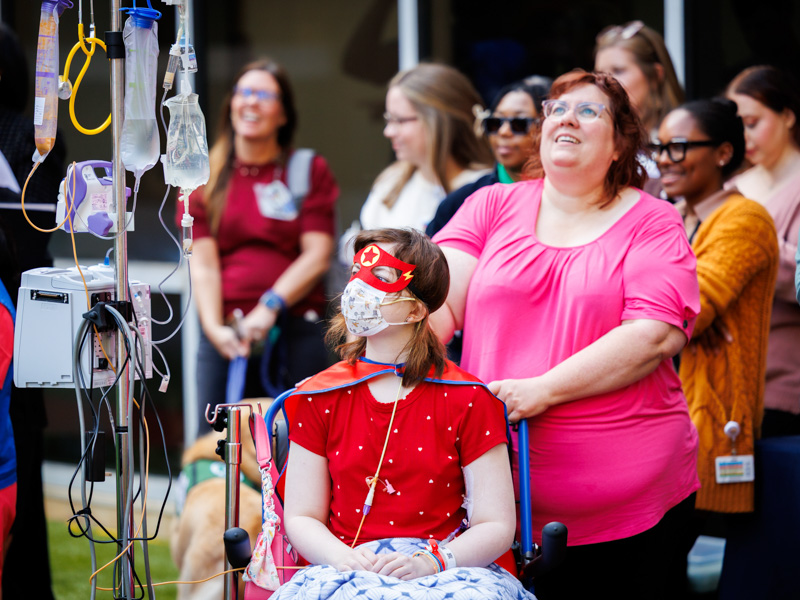 Mikayla Sweet of Kosciusko and her mom, Melisa, watch as superheroes from the Mississippi Fire Academy rappel to Mimi's Playground.