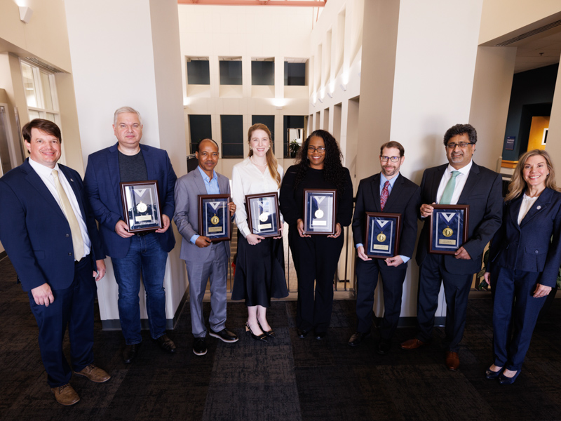 Dr. Lee Bidwell, left, associate vice chancellor for research, and Dr. Caroline Compretta, right, assistant vice chancellor for research, honor gold medallion winners, from left, Dr. Alexandre da Silva, associate professor of physiology and biophysics; Dr. Wondwosen Yimer, associate professor of data science; Dr. Lais F. Berro, assistant professor of psychiatry; Dr. Tearsanee C. Davis, director of clinical programs and strategy for the UMMC Center for Telehealth; Dr. Andrew C. Voluse, associate professor of psychiatry; and Dr. Ajay Singh, professor of cell and molecular biology and associate director of basic and translational research at CCRI.