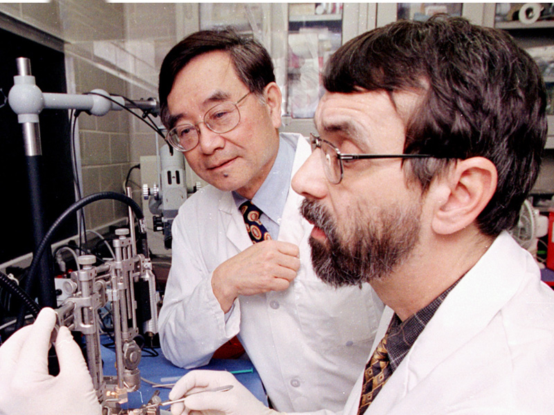 Dr. Ing Ho, inaugural dean of the School of Graduate Studies in the Health Sciences, watches as Dr. Rob Rockhold, former professor in the Department of Pharmacology and Toxicology, performs an experiment in this archival photo.