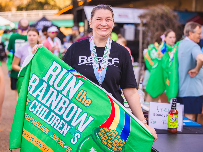Josie Bidwell, clinical director, department of Preventive Medicine, holds the 2026 Run the Rainbow post-race finisher blanket.