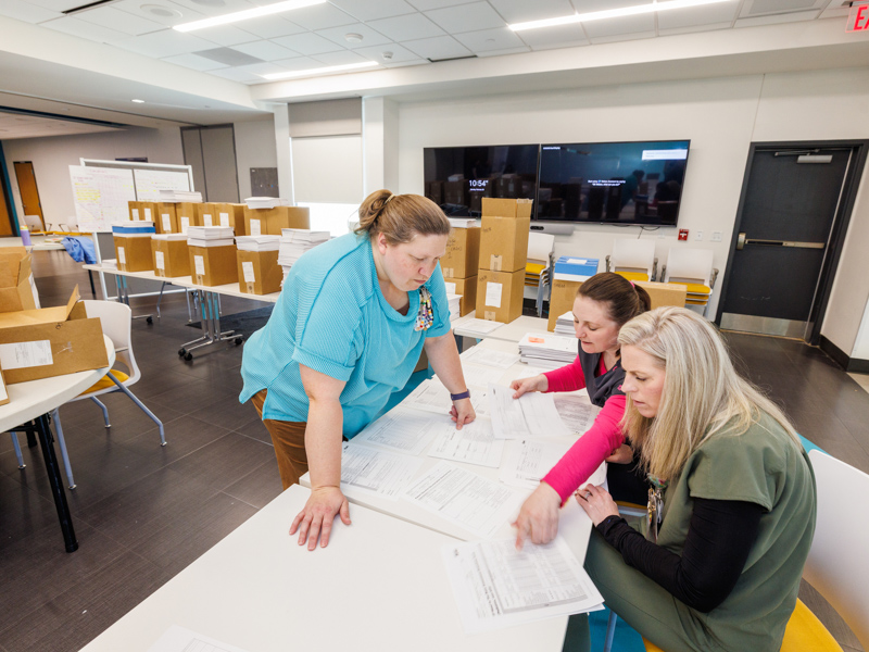 Olivia Ulbrich, project manager for child life, Shanna Kennon, shift supervisor at the Clarke Center, Brittany Harwell, clinical outcomes coordinator at the Clarke Center put together binders of paperwork to be used at the Clarke Center.