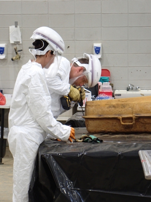 Lead Bioarchaeologist, Jennifer Mack and machine operator, Johnny Bass, spent hours using a drill to open the cast iron casket.