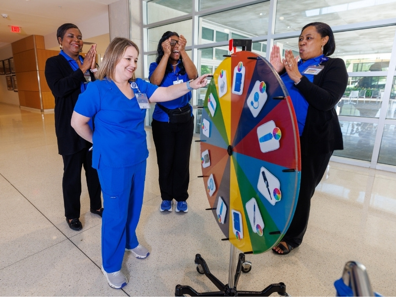 UMMC Employees, from left, Renee Stevens, Brandi Granderson and Shonna Mondy from Human Resources, cheer on Jessica Martinez, assistant professor of occupational therapy, as she spins for her prize during Employee Appreciation Week. Jay Ferchaud/ UMMC Communications