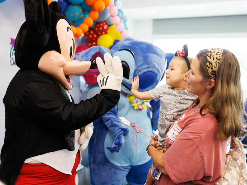 Allyson Ulery, 3, of Bogue Chitto high fives Mickey Mouse at Disney Day hosted in the Sanderson Tower Community Room in the children's hospital.