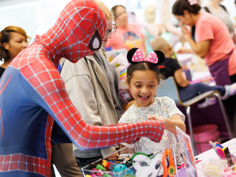 Avery Etheridge of Liberty makes a craft with Spiderman at Disney Day hosted in the Sanderson Tower Community Room located in the children's hospital.
