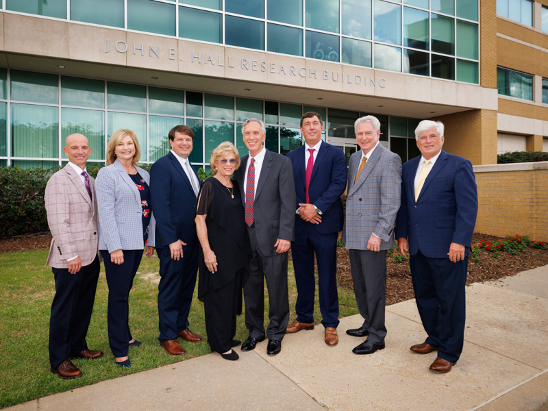Colleagues celebrate a milestone that ensures Dr. Hall's legacy will inspire future generations of students, researchers and physicians. They are Dr. Alan Jones, left, Dr. LouAnn Woodward, Dr. Lee Bidwell, Becky and Dr. John Hall, Dr. Michael Hall, Dr. Dan. Jones and Dr. Joey Granger. Joe Ellis/ UMMC Communications