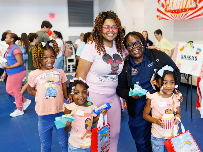 Dr. Bolaji Famuyide, chief of pediatric neonatology, poses with Tyanna Williams and her daughters, Taylyn Williams, 9, who spent almost a year in the NICU at Children's, Tarozi and Tyli Williams at the NICU reunion.