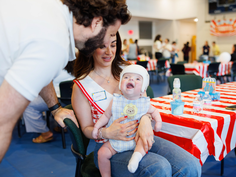Former NICU patient Abe Malouf is all smiles with his parents, Sarah and Matt Malouf, at the circus-themed NICU reunion.