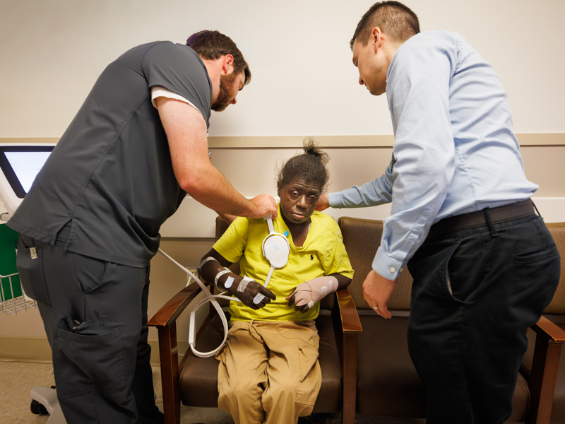 Yen examines Daisy Knight of Natchez during a dialysis visit while Thomas Hudson, clinical research coordinator, assists.