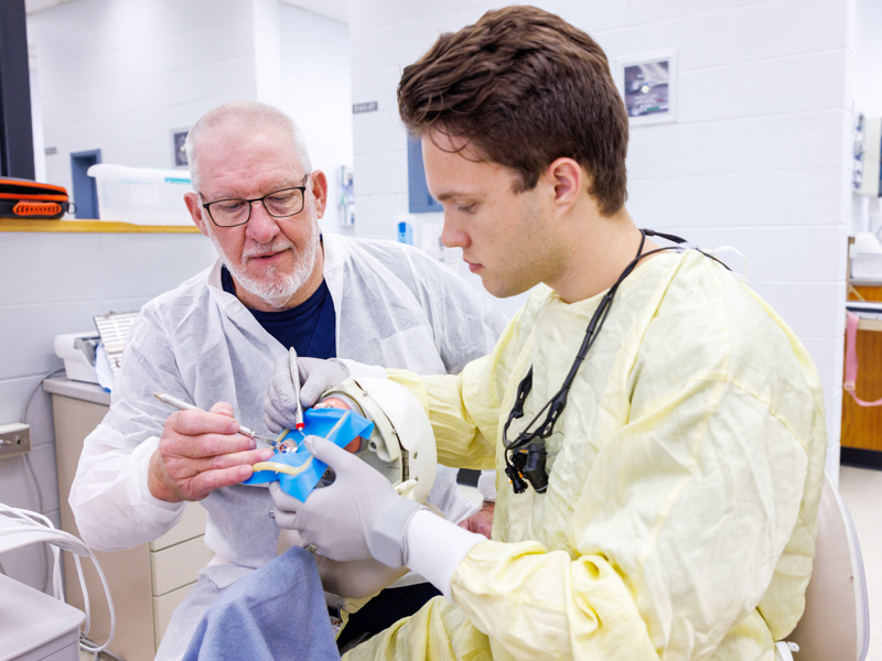 Dr. Hiram Gatewood trains third-year student Jameson Cook for root canals using a simulator.