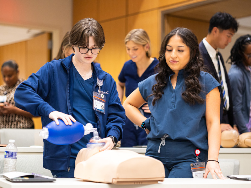 Caroline McKinney, left, and Kimberly Vazquez, first-year medical students, learn basic life support skills during Welcome Week orientation, gaining hands-on experience as they prepare to begin their medical education at UMMC. Belle Grace Wilkinson/ UMMC Communications