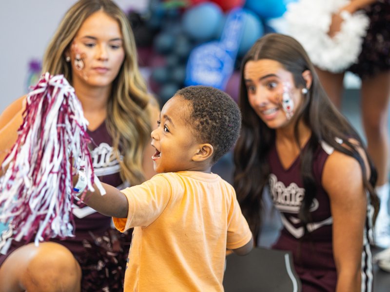 Asher Henley, 2, of Columbus shows off his pom to Mississippi State University cheerleaders.