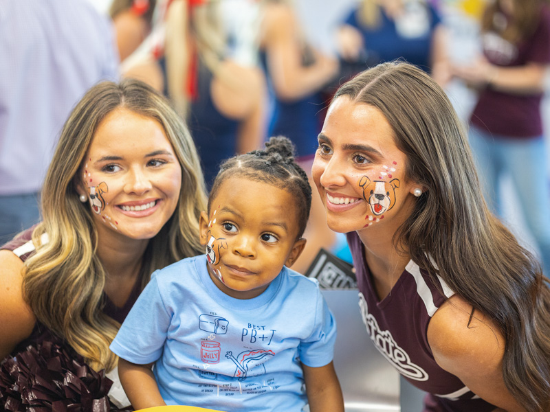 Kaidyn Bruce, 2 shows off his Bully Bulldog face paint to Mississippi State University cheerleaders.
