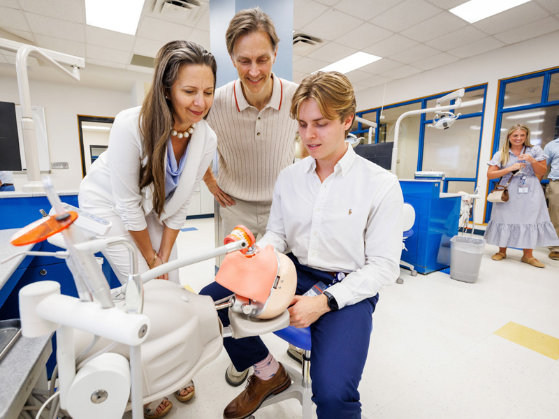 Incoming Class of 2030 dental student Elijah McIntyre, seated, tours the simulation lab with his parents, former UMMC School of Dentistry graduates, Rayline and John McIntyre. Jay Ferchaud/ UMMC Communications