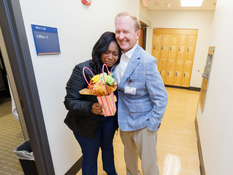 A surprise 25 years in the making brought tears to Ebony Gaston, nurse manager of UMMC's radiation oncology ambulatory clinic. Congratulating her is Trey Woods, radiation oncology business and operations administrator.