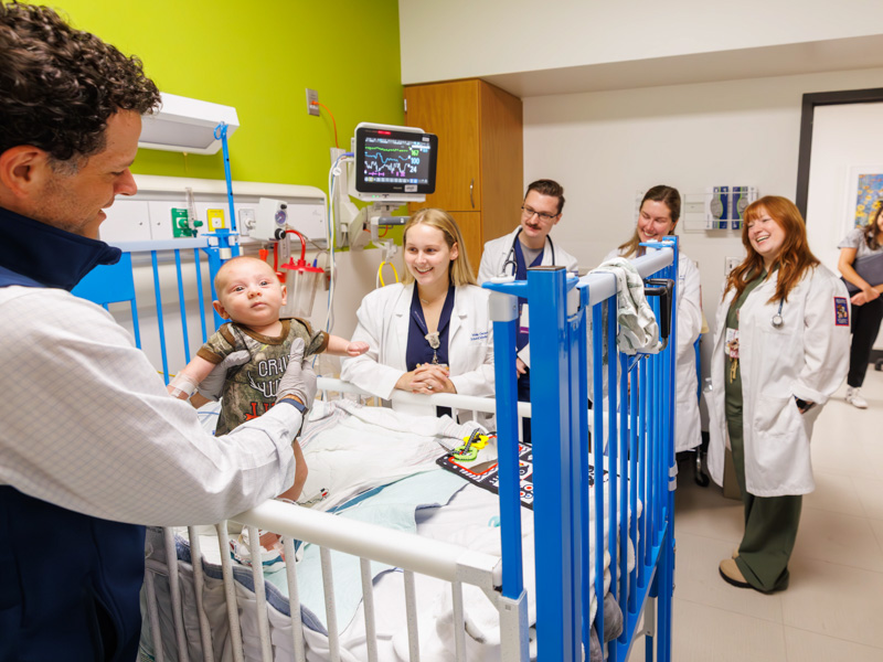 Dr. Mitchell Hobbs, director of the pediatric hospital medicine fellowship program, evaluates Maverick Hopkins during morning rounds with his team of house officers, residents and medical students at the children's hospital.