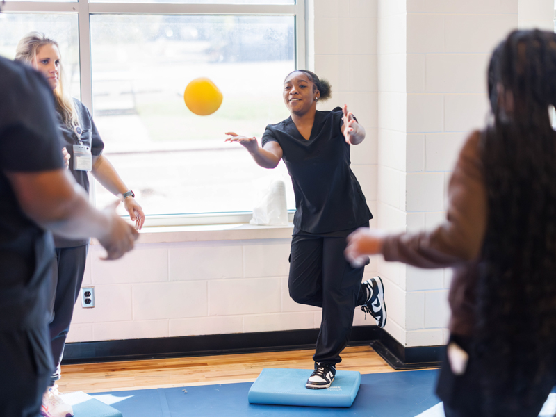 Hattiesburg High School junior Cambree Adams shows off her balance skills with classmates and Ashlyn Gilreath, assistant professor of physical therapy, during Discovery Day.