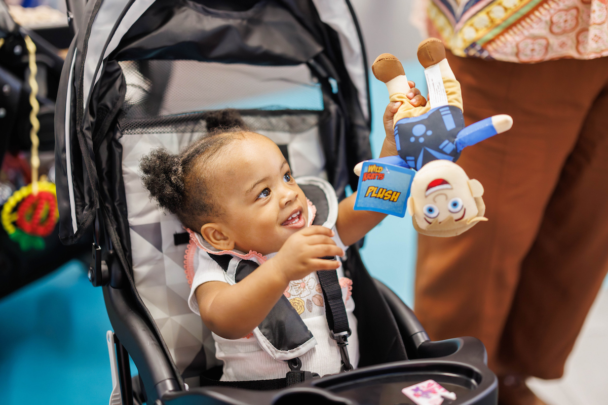 Jazaria Vanburen, 1, of Carthage checks out her prize after winning a fair game during Fair with Friends at the children's hospital.