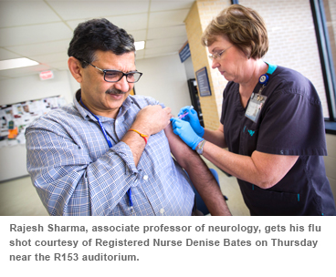 Rajesh Sharma, associate professor of neurology, gets his flu shot courtesy of Registered Nurse Denise Bates on Thursday near the R153 auditorium.