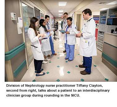 Department of Nephrology nurse practitioner Tiffany Clayton, second from right, talks about a patient to an interdisciplinary clinician group during rounding in the SICU.