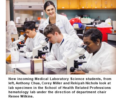 Students in lab coats gathered around a microscope, engaged in scientific exploration and teamwork in a laboratory environment.