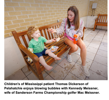 Children's of Mississippi patient Thomas Dickerson of Pelahatchie enjoys blowing bubbles with Kennedy Meissner, wife of Sanderson Farms Championship golfer Mac Meissner.