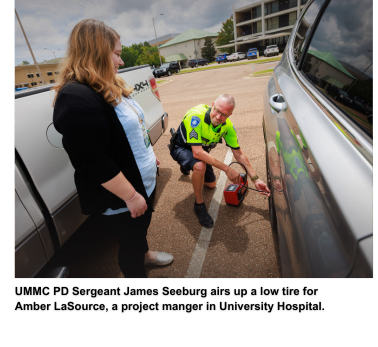 UMMC PD Sergeant James Seeburg airs up a low tire for Amber LaSource, a project manger in University Hospital.