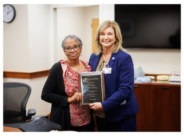 Ms. Verlyne Broadway is awarded a plaque by Dr. Lou Ann Woodward to recognize her 55 years of service.