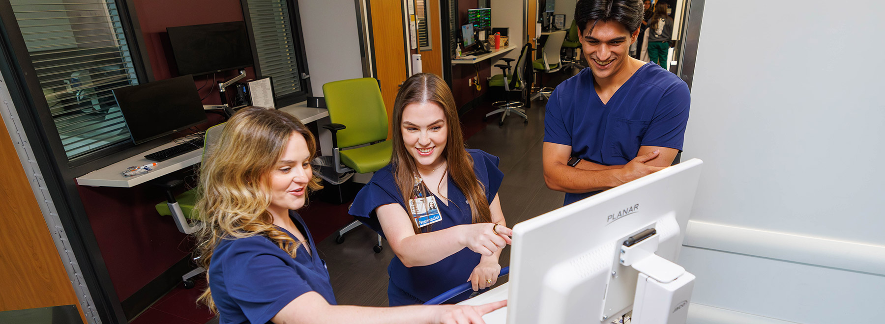 Three UMMC-based pharmacy residents review data on a monitor.