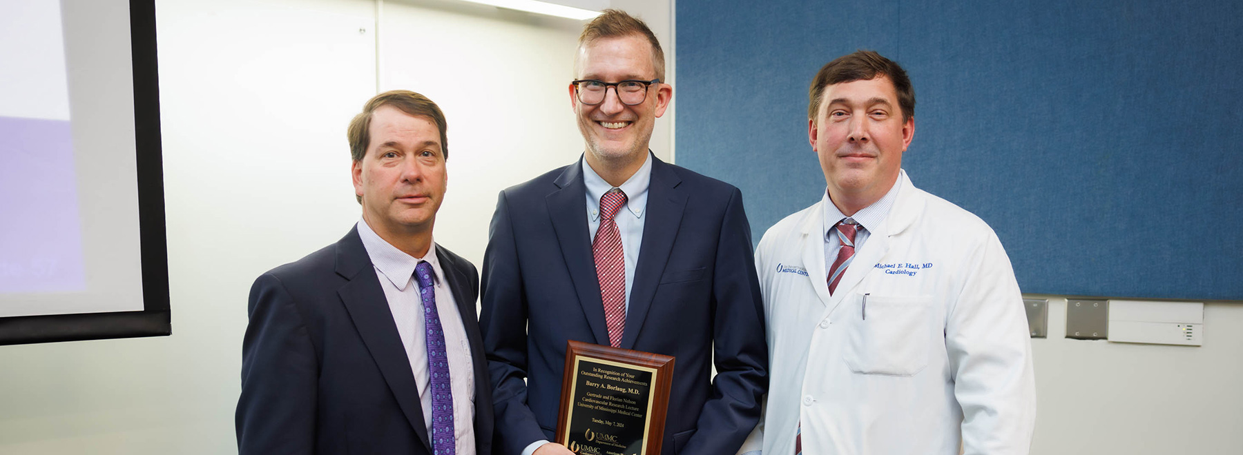 Dr. David Stec, Dr. Barry A. Borlaug holding an award, and Dr. Michael Hall.