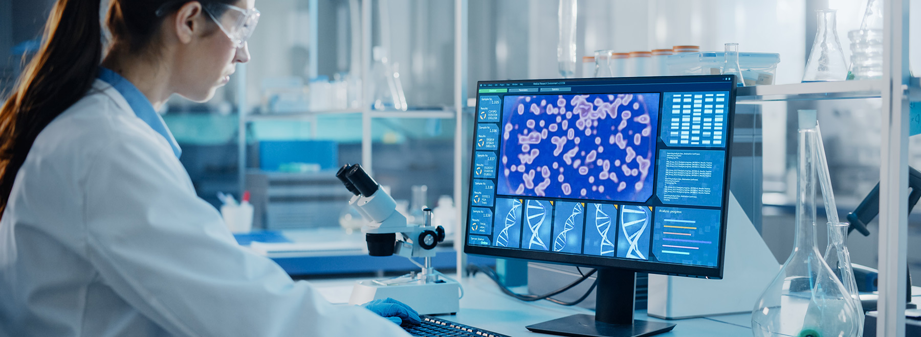 A microbiologist working on a computer with a display showing a gene editing interface.