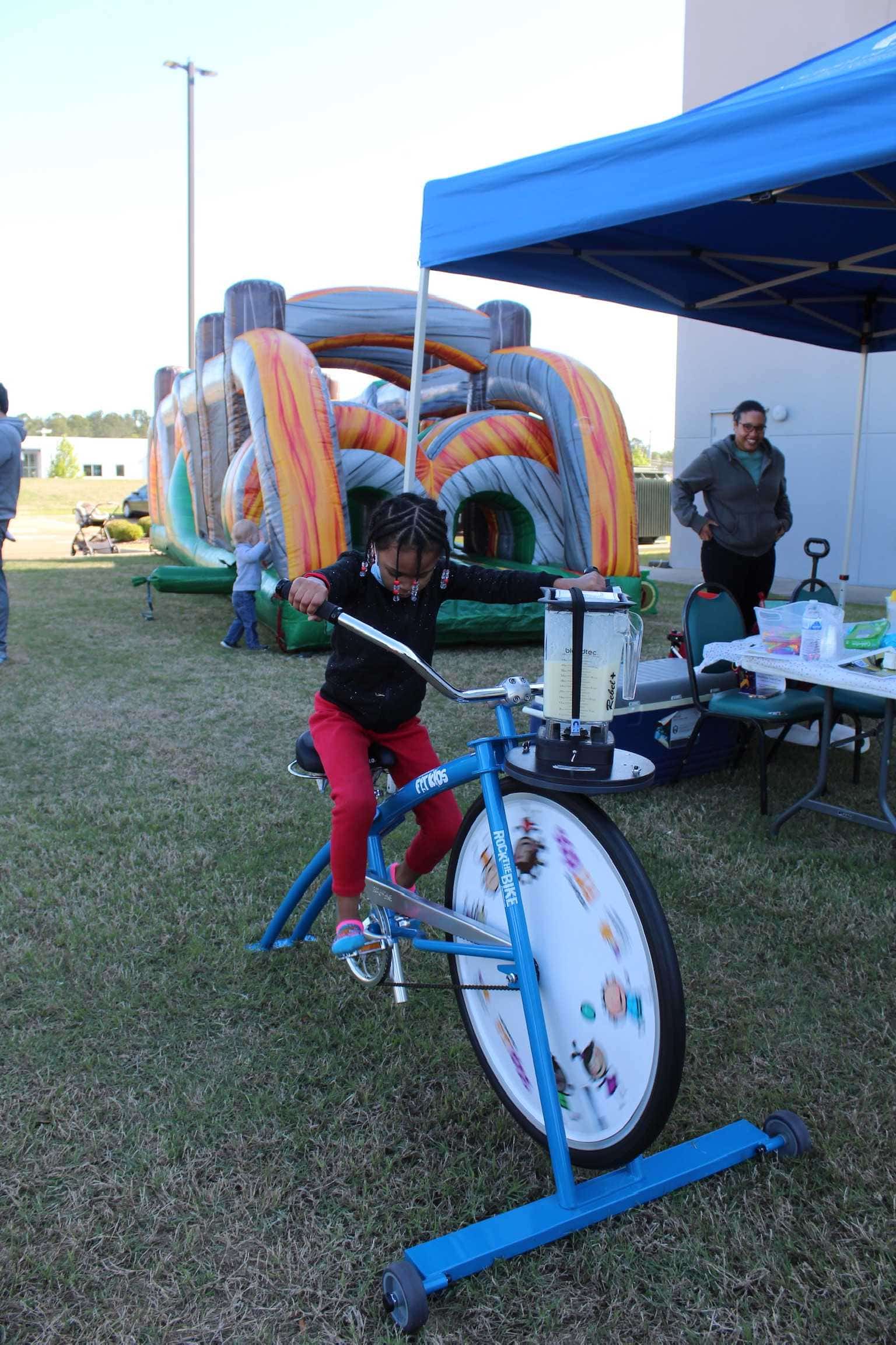 Child riding a stationary bike with a large front wheel.