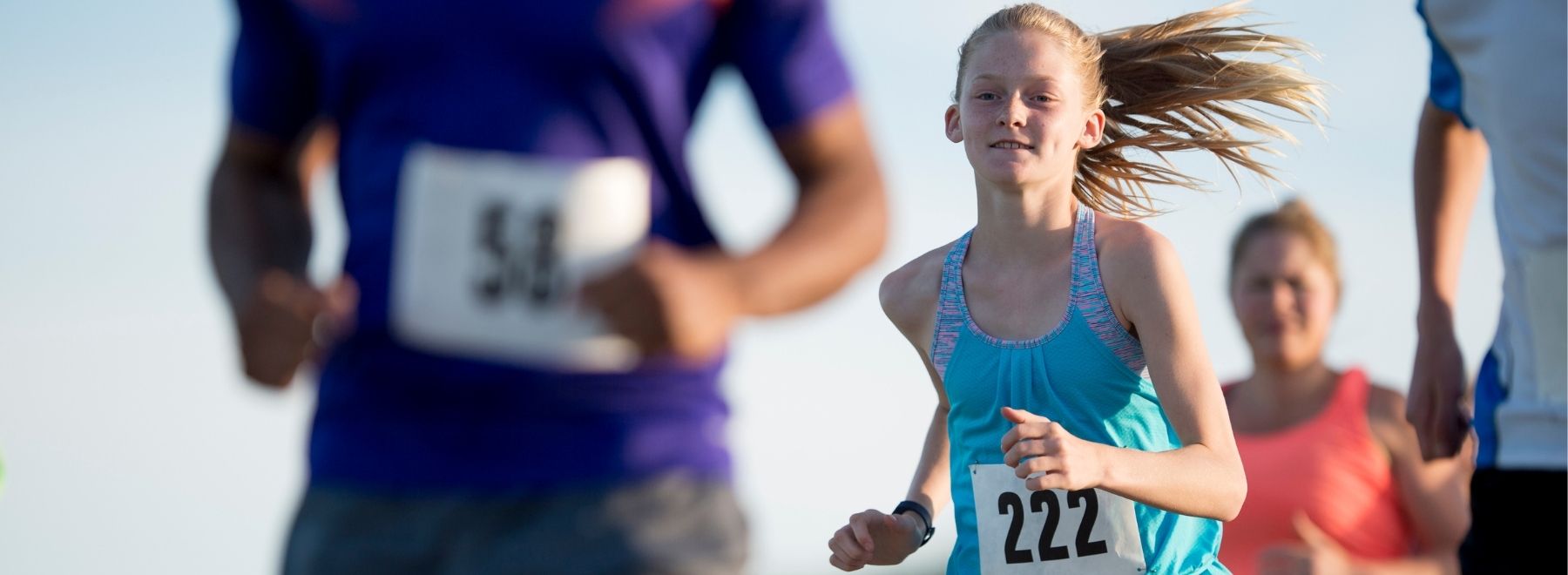 Young girl smiling while running 5K marathon with adults