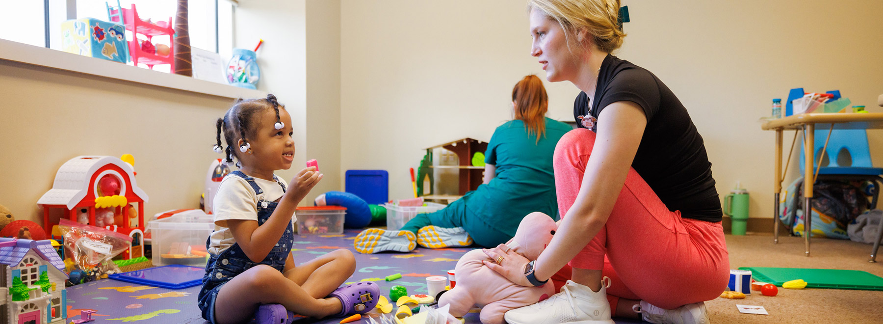 A specialist interacts with a child during a therapy session.