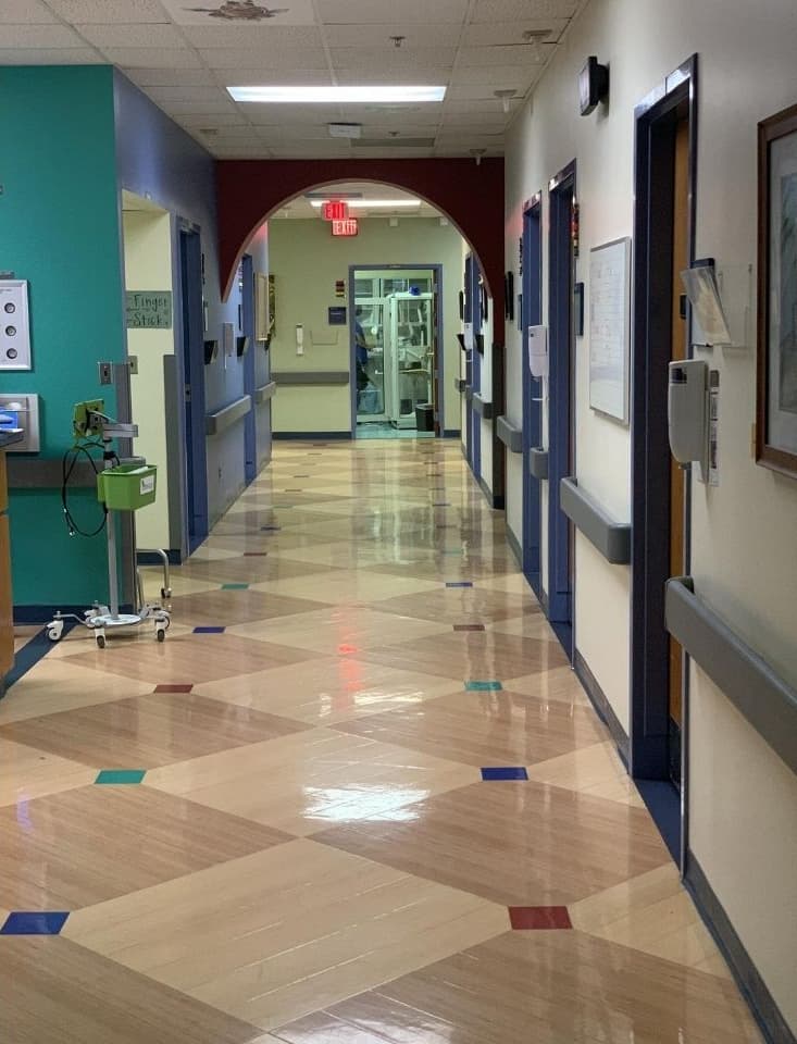 A hallway in the clinic has brightly patterned color blocks on the floors and purple arches at the ceilings.