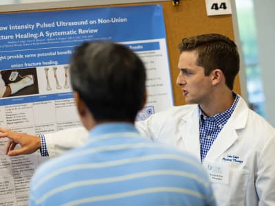 A physical therapist discusses his research poster.