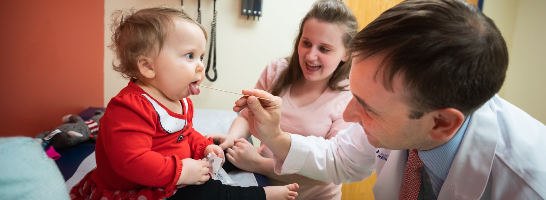 Provider uses tongue depressor during a Child's check-up.