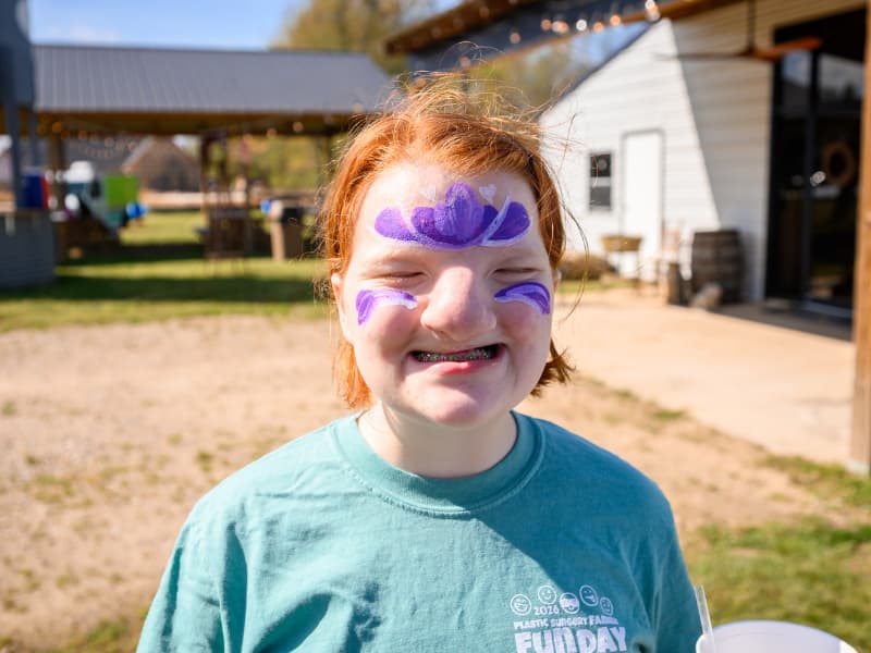 A girl with braces smiles for the camera and shows off her face paint at Family Fun Day 2026.