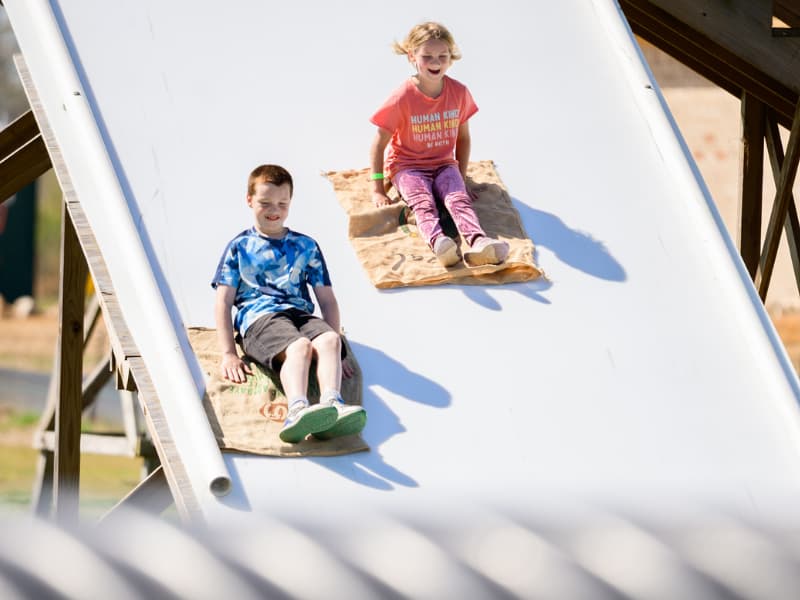 A boy and girl go down the slide at Family Fun Day 2026.
