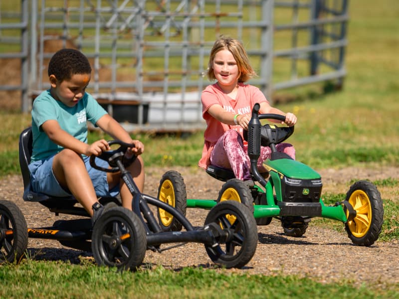 A boy and girl ride toys that look like tractors at Family Fun Day 2026.